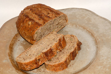Half a loaf and slices of seven grain bread on rustic ceramic plate