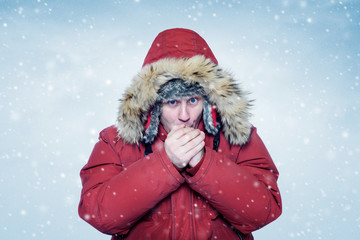 Man in winter clothes warming hands, cold, snow, blizzard