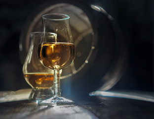 Two glasses of strong alcohol and oak barrel