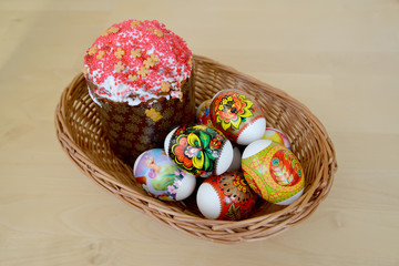 Colored Easter eggs and Easter cake in a wattled support on a li