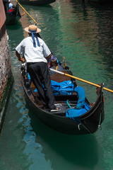 Fototapeta na wymiar Gondolier in Typical Canal in Venice, Italy