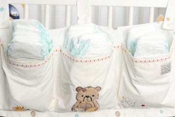 Stack of diapers in bags on a baby bed
