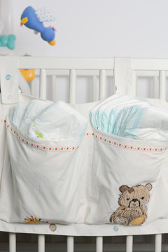 Stack of diapers in bags on a baby bed