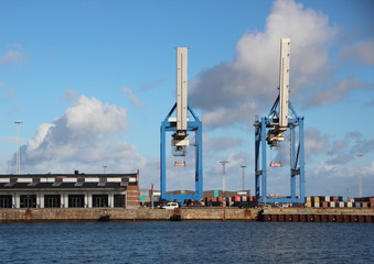 Fototapeta na wymiar Container Cranes at Harbor Pier with Water Front