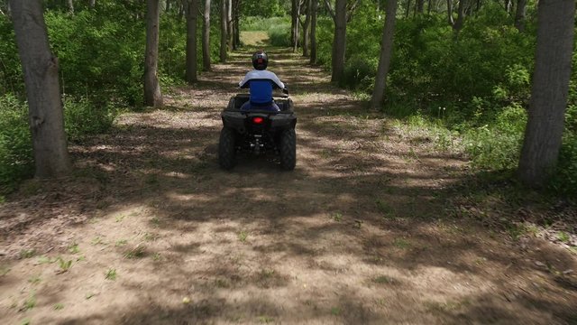 Young man driving quadbike in the forest.
