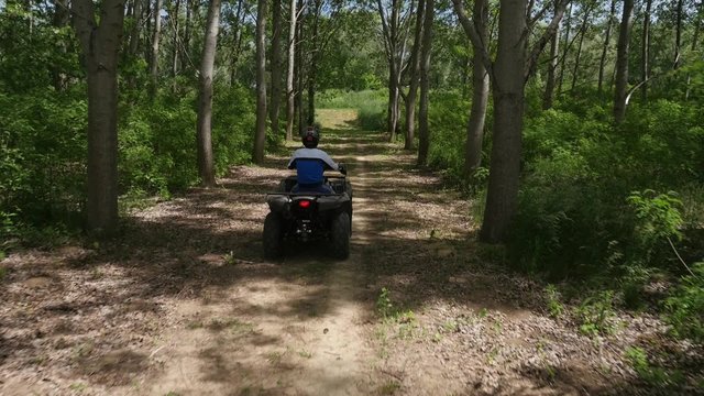 Young man driving quadbike in the forest.
