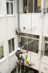 vertical worker  in motion on courtyard  with safety system for repair pipes
