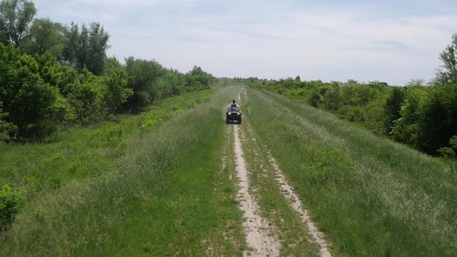 Young man driving quadbike in the forest.
