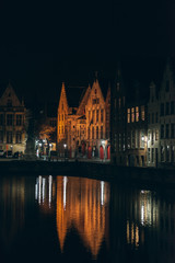 Fototapeta na wymiar Illuminated Buildings by Canal at Night in Bruges