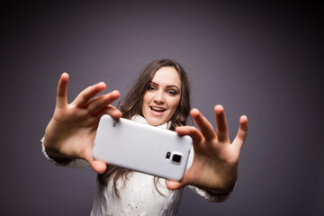 Naklejka premium Portrait of a young attractive woman making selfie photo on smartphone isolated on a white background