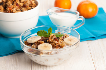 Granola with yogurt and banana in a bowl on wooden background