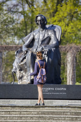 Young woman standing near Chopin statue