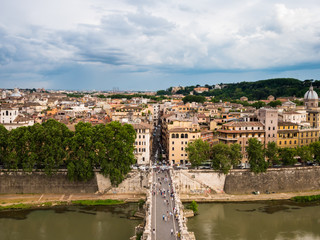 Fototapeta na wymiar A view from above of the capital city of Rome in Italy. You also get a clear view of tourists on the Bridge of Hadrian (Ponte Sant’Angelo) - the bridge filled with angel statues.