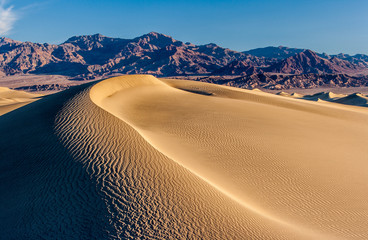 Fototapeta na wymiar sand dunes with ripples, mountain, sky