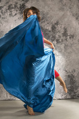 Female dancer in a turn with dark blue fabric.