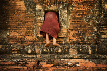 Buddhist novice monk climbing into monastery