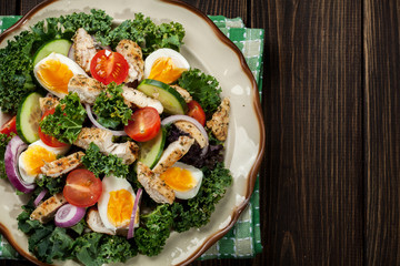 Fresh salad with chicken, tomatoes, eggs and lettuce on plate