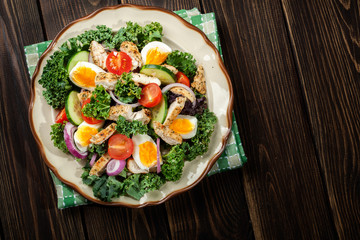 Fresh salad with chicken, tomatoes, eggs and lettuce on plate