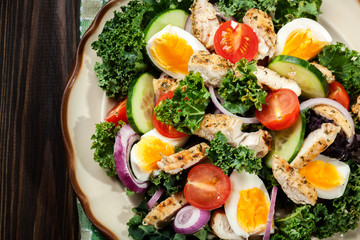 Fresh salad with chicken, tomatoes, eggs and lettuce on plate
