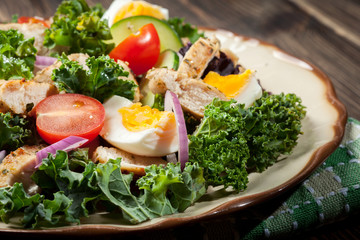 Fresh salad with chicken, tomatoes, eggs and lettuce on plate