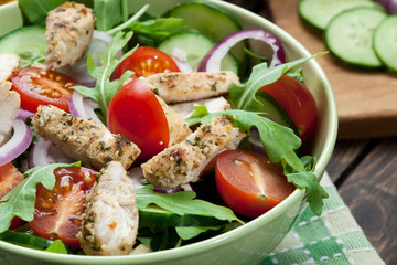 Fresh salad with chicken, tomatoes and arugula on plate