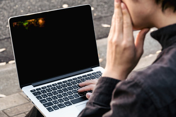 ラップトップを見て考える男性