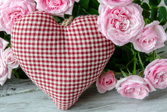 Checked handmade heart against of red and pink roses