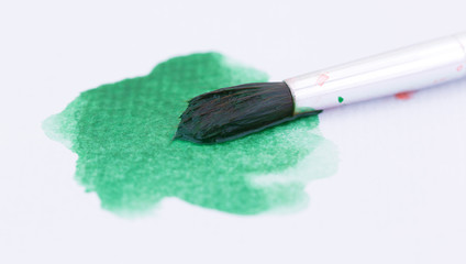 Green watercolor paint and brush on paper
