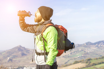 hiker in the mountains drinking water from his water bottle - caucasian people - people, drink and nature concept