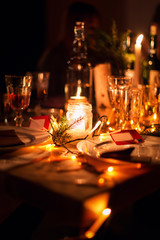 Decorated Christmas holiday table ready for dinner. Beautifully decorated table set with candles, spruce twigs, plates and serviettes for event in the restaurant.