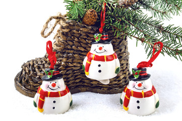 Christmas wiker boots, three snowman and fir cones on a white background