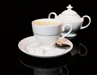 Cup of coffe and sugar bowl on black background