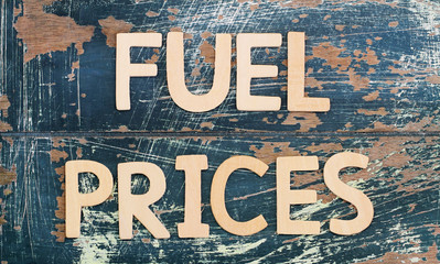 Fuel prices written with wooden letters on rustic surface
