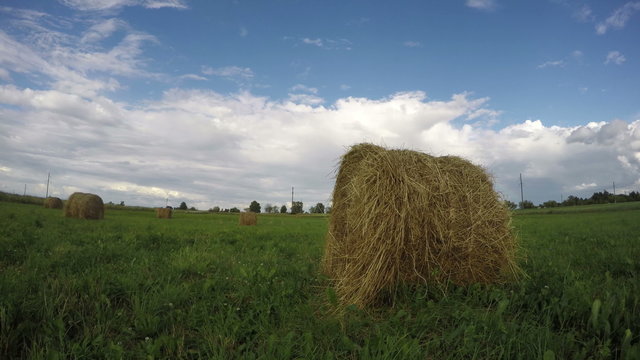 Meadow full of haystacks on cloudy sunny summer's day, 4K time lapse