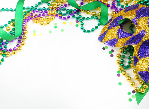 Mardi Gras image of harlequin mask, beads, ribbon and confetti in gold, green and purple