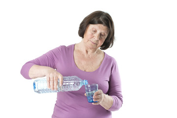 Elderly woman drinking water pours into the glass..