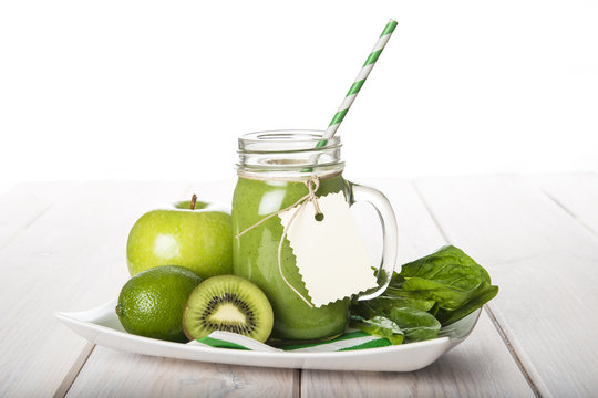 Green smoothie o batido verde con frutas y hojas para una dieta vegetariana adelgazan en una mason jar con pajita espiral 