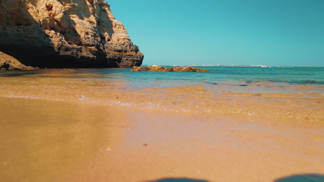 Inspirational slider low angle shot of a desert beach in the Algarve, Portugal. A recreational boat can be seen in the background

