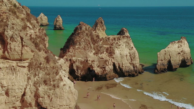 A wide angle static shot of a rocky beach with turquoise waters in the Algarve, Portugal

