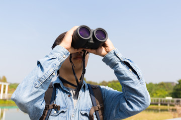 Man using binoculars for birdwatching - obrazy, fototapety, plakaty
