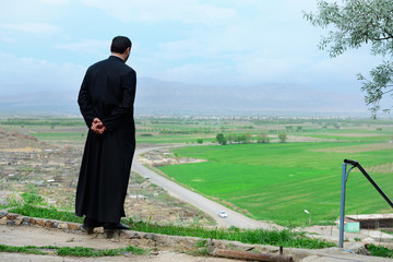 Armenian priest overlooking scenic fields and mountains