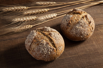 Bread and wheat ears on wooden background