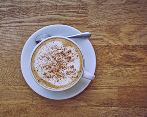 Cappuccino in white cup close-up on wood background