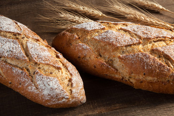 Bread and wheat ears on wooden background