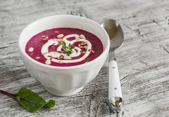 beet soup in a white bowl on bright wooden surface - healthy food