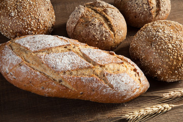 Bread and wheat ears on wooden background