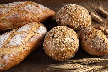 Bread and wheat ears on wooden background