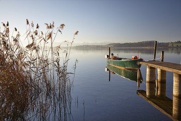 Stimmungsbild vom Pfäffikersee mit vertäutem Fischerboot, Bootssteg, Schilfrohr, und entferntem Seeufer