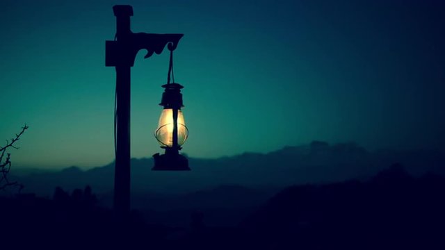Lantern at twilight with mountains in the background. Cinemagraph seamless loop.