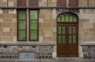 Ornate, wooden doorway and window in stone building in Belgium	